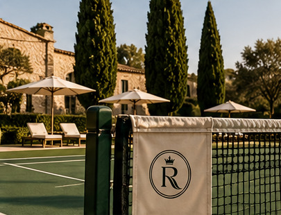 Court net with emblem banner beside cypress trees and parasols